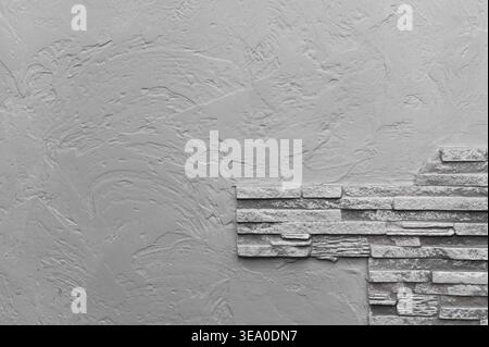 Textured gray wall with stone cladding on one side, creating modern and minimalistic design. creative concrete backdrop. rough stone pattern, adding v Stock Photo