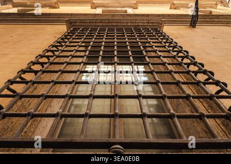 Low angle view of historic iron barred window on classical stone facade in Rome Italy Stock Photo