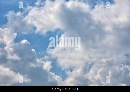 Beautiful natural background of white soft clouds floating in a vibrant blue summer sky. High resolution texture. Stock Photo