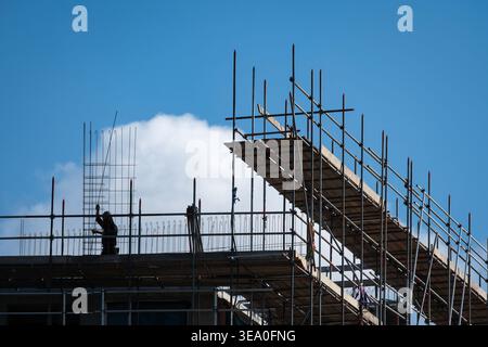 Scaffolding on buiding site and construction worker in silhouette Stock Photo