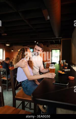 Couple enjoying drinks and snacks at bar counter in pub Stock Photo
