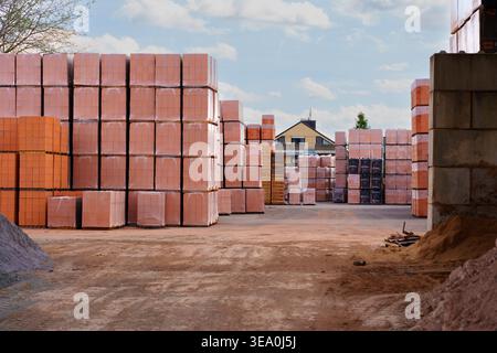 Hainstadt, Germany - April 5, 2026: Many stacked pallets of orange clay building blocks are ready for transport at a very large industrial manufacturi Stock Photo