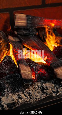 Fire burns brightly with glowing embers and logs at a cozy gathering in the evening Stock Photo