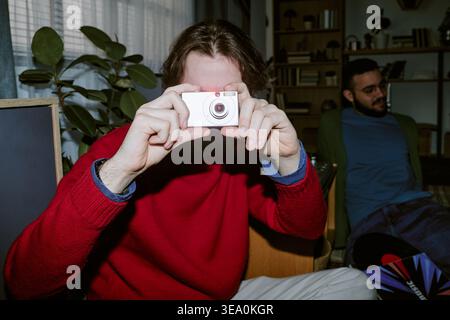 Adult Man Holding Compact Camera and Taking Casual Indoor Photo Stock Photo