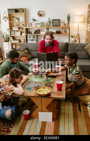 Diverse Adult Friends Playing Tabletop Game during Social Gathering Stock Photo