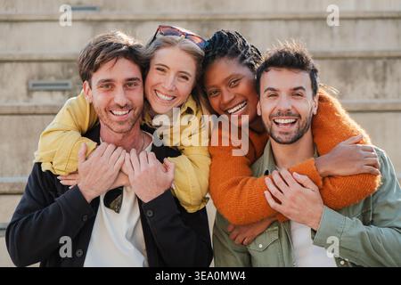 A group of close friends enjoying a delightful moment filled with laughter and joy as they embrace each other warmly in a fun and playful manner Stock Photo