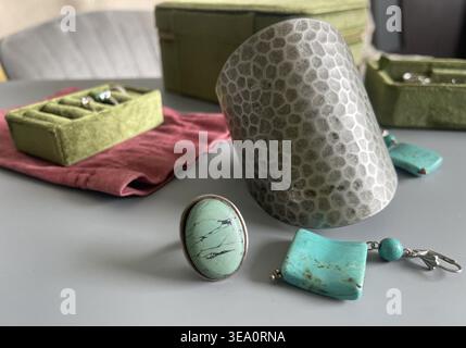 Several pieces of jewelry are arranged on a table, including a ring with a turquoise stone, a bracelet, and some earrings. A green box with compartmen Stock Photo