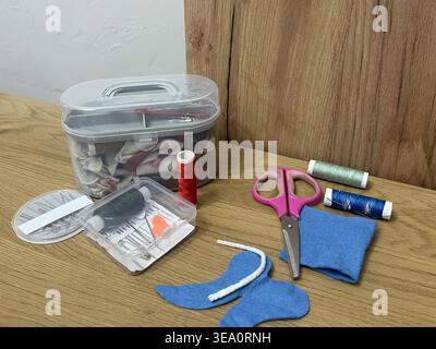 A tailor's sewing kit on a table. Needles, thread, and fabric for sewing. Stock Photo