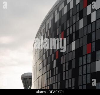 Modern curved facade with geometric mosaic pattern. Close-up of a contemporary building's curved glass and metal exterior, featuring a rhythmic mosaic Stock Photo