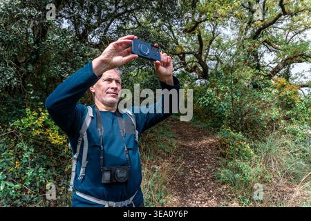 Man hiking enjoying nature capturing image with smartphone Stock Photo