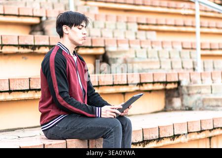 Young student analyzing information on digital tablet outdoors Stock Photo