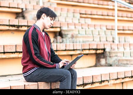 Young man studying outdoors using digital tablet Stock Photo