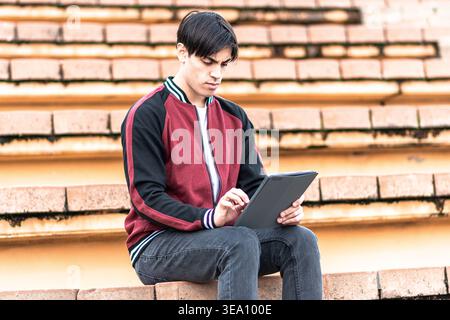 Young student learning outdoors using digital tablet Stock Photo