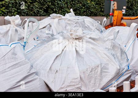 Close up of construction waste materials packed into white woven bulk sacks, stacked outdoors at a work site Stock Photo