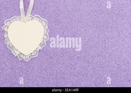 White lace heart ornament on purple glitter textured background creating romantic, soft, and elegant design for love themed projects and holidays Stock Photo