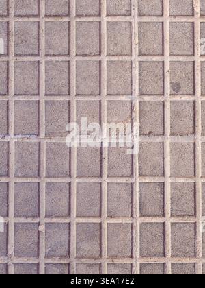 Grey concrete blocks forming a repeating square grid pattern create a rough, textured surface, providing an industrial and urban background in almasso Stock Photo