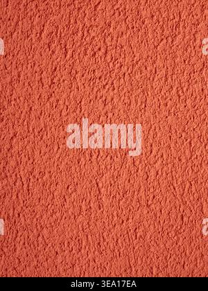 Orange red textured wall surface showing a rough stucco finish, creating a vibrant pattern suitable for backgrounds and abstract concepts in almassora Stock Photo