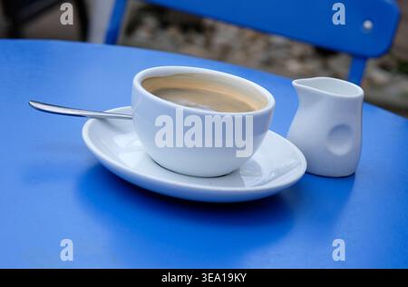 white coffee cup and saucer on blue table top Stock Photo