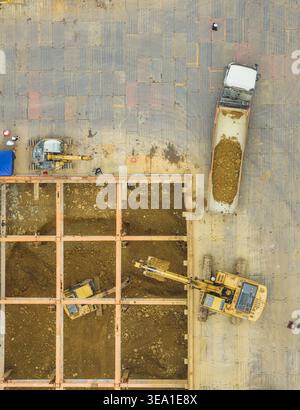 Aerial view of excavators working on building foundation engineering with a dump truck, steel beams and workers on a construction site in Taiwan. Stock Photo