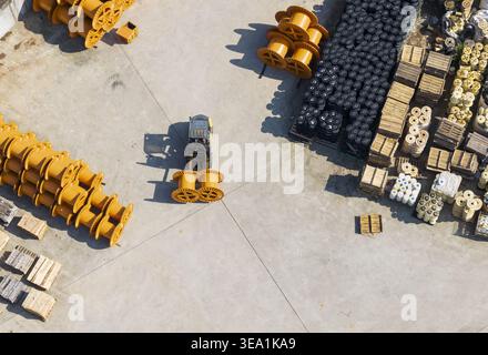 Aerial view of a cable factory with a forklift operator moving large yellow cable spools in an industrial yard in Taiwan. Stock Photo