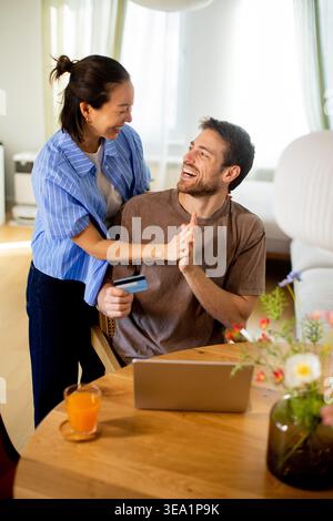 Happy couple sharing laptop at dining table Stock Photo - Alamy