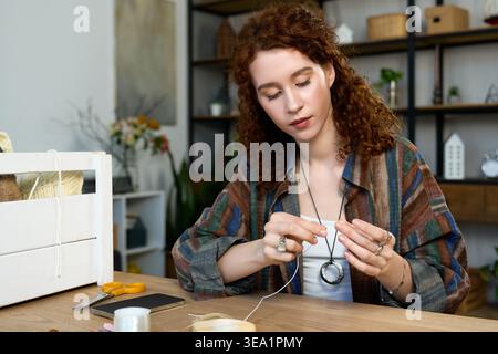 A dedicated woman expertly immerses herself in her handmade hobby with creative tools around. Stock Photo
