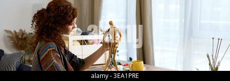 A woman enjoys her creative side, skillfully working on a handmade project with joy. Stock Photo