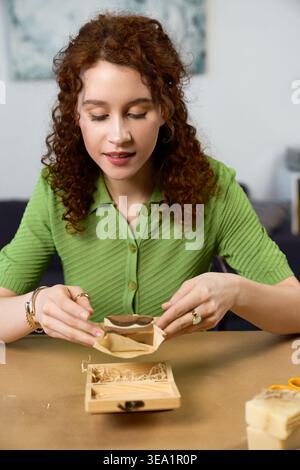 A beautiful woman engages in her favorite handmade hobby, creating art with joy and focus. Stock Photo