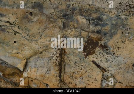 Close-up of weathered stone surface with natural cracks and earthy tones creating abstract texture Stock Photo