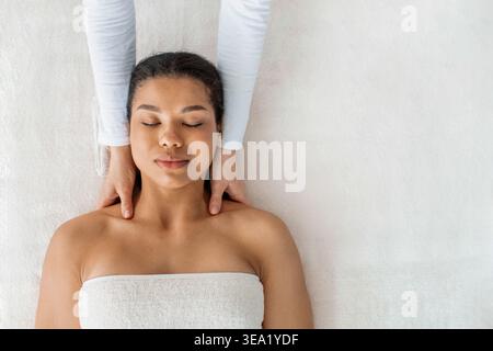 Top view of young African American woman receiving neck massage at spa Stock Photo