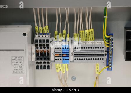 A bunch of wires are connected to a box with yellow labels. Electrical panel, contacts, switches, commutation. Stock Photo