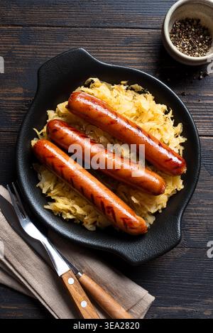 Stewed cabbage, sauerkraut and grilled sausages on wooden table, top view, copy space. German cuisine, Oktoberfest meal. Stock Photo