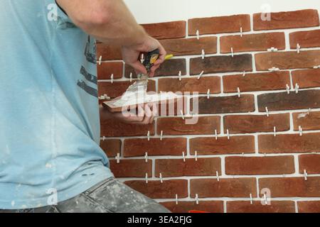 Professional builder gluing decorative brick on wall, closeup. Tiles installation process Stock Photo