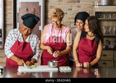Chefs cutting vegetables and having fun during cooking course Stock Photo