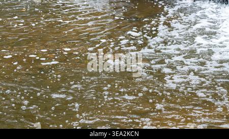 A tranquil nature scene capturing delicate bubbles forming and floating downstream, created by a small unseen waterfall just beyond the frame. The ima Stock Photo