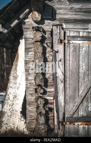 A weathered wooden cabin's side, showing the door, log construction, and textures with rustic charm. Stock Photo