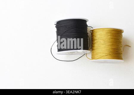 Top view of two thread spools placed on a clean white table. Minimalist composition highlighting texture, symmetry, and sewing materials. Ideal for co Stock Photo