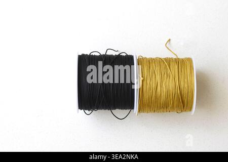 Top view of two thread spools placed on a clean white table. Minimalist composition highlighting texture, symmetry, and sewing materials. Ideal for co Stock Photo