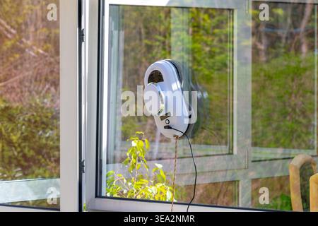 Robotic window cleaner cleans glass on open plastic window in residential home. Stock Photo
