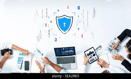 Team members collaborate in a modern office, discussing cybersecurity strategies while analyzing data on various devices. A shield icon symbolizes Stock Photo