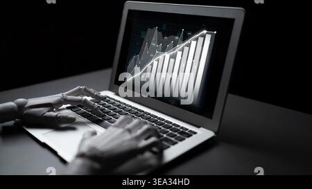 A robotic hand interacts with a laptop, displaying financial graphs that represent data analysis and technological advancement in modern business Stock Photo