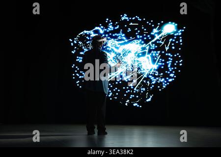 Programmer monitoring AI cognitive systems using VR headset gear. IT specialist using virtual reality AR simulation to study neural network nodes activity and understand data processing algorithms Stock Photo