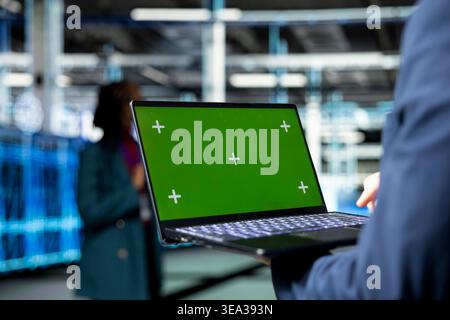 Green screen laptop used by programmer in data center to monitor rigs metrics. Employee in server room using mockup notebook device to enhance operational effectiveness of IT infrastructure, close up Stock Photo