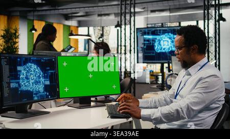 Green screen mockup PC used by data scientist in office automating workflows with artificial intelligence. IT worker refines deep learning models on chroma key computer for faster processing, camera A Stock Photo
