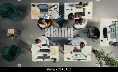 Top down view of coworkers engaged in consulting and report sharing at office. Professional team reviews visual data and documents to enhance business strategy and performance goals. Stock Photo