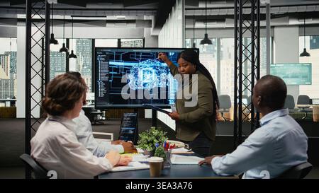 System administrator presents AI chatbot reducing work volume to executives. African american startup IT specialist analyzing business insights for management using artificial intelligence, camera A Stock Photo