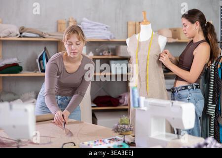 Women tailors design clothes and draw on paper in the workshop Stock Photo