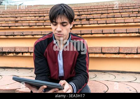 Young man sitting on steps using digital tablet Stock Photo