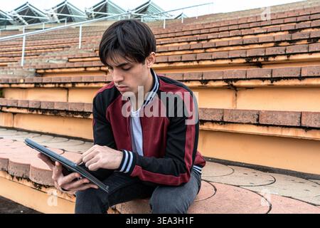 Young man using digital tablet on stadium steps Stock Photo