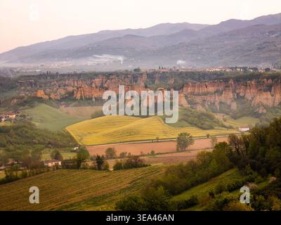 Aerial view of the unique Le Balze rock formations and rolling green hills with yellow fields under a soft morning light in Piantravigne, Tuscany, Ita Stock Photo